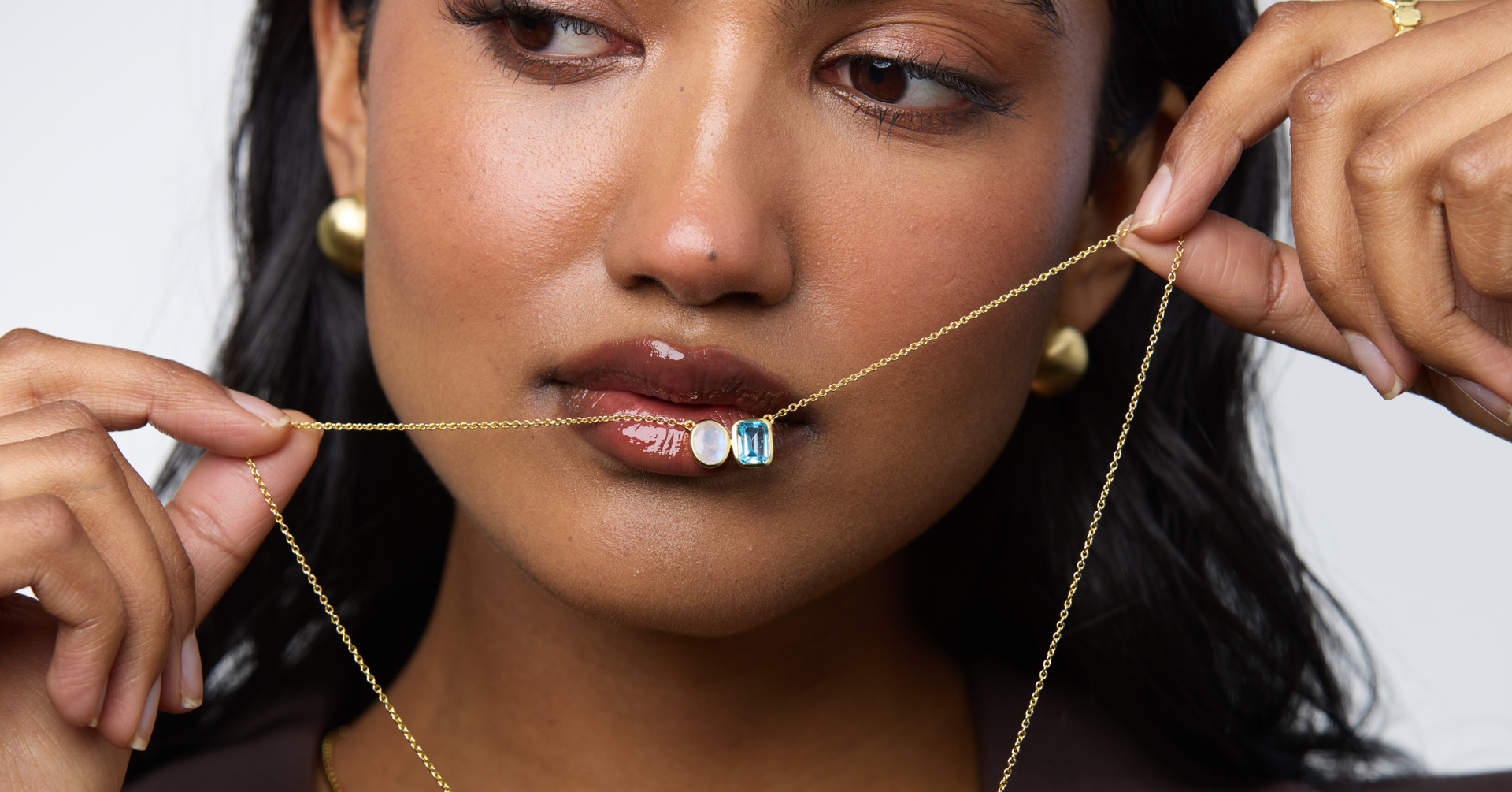 Girl holding up a gold double gemstone necklace
